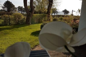 A garden with a lawn, trees, and a body of water in the background. - Holiday apartment with 1 bedroom (Travemünde)
