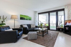 A modern living room with a sofa, coffee table, and a television. - Holiday apartment with 1 bedroom (Travemünde)