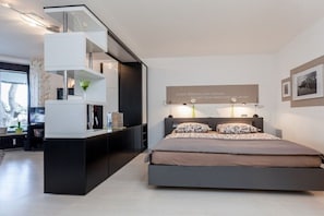 A modern bedroom with a bed, bedside tables, and a built-in shelving unit. - Holiday apartment with 1 bedroom (Travemünde)