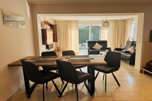 A dining area with a table and chairs, a sofa, and a view of the outdoors. - Holiday home with 2 bedrooms (Sierksdorf)