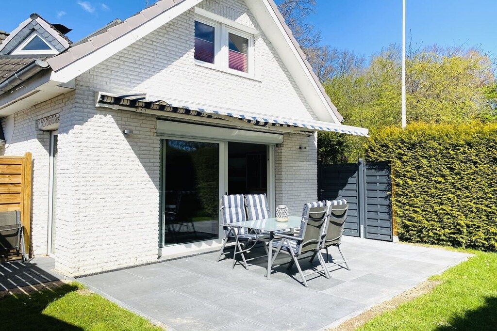 A house with a patio, a dining table with chairs, and a garage door.
