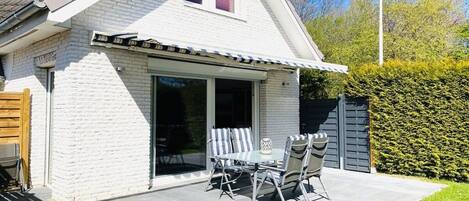 A house with a patio, a dining table with chairs, and a garage door.