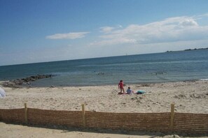 Een strand met een houten omheining, zandstrand en rustige zee.