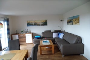 Een moderne woonkamer met een bank, salontafel en eethoek.