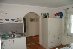 A kitchen with a sink, cabinets, and a window with a curtain. - Holiday home by the sea (Fehmarn)
