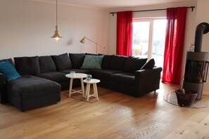Ein modernes Wohnzimmer mit einer Eckcouch, einem kleinen runden Tisch, einer Stehlampe und einem Kamin.