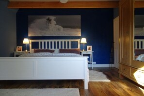A bedroom with a white bed, two bedside tables with lamps, a large painting on the wall, and a wooden wardrobe. - 4 holiday farm at Hemmelsdorfersee (Offendorf)