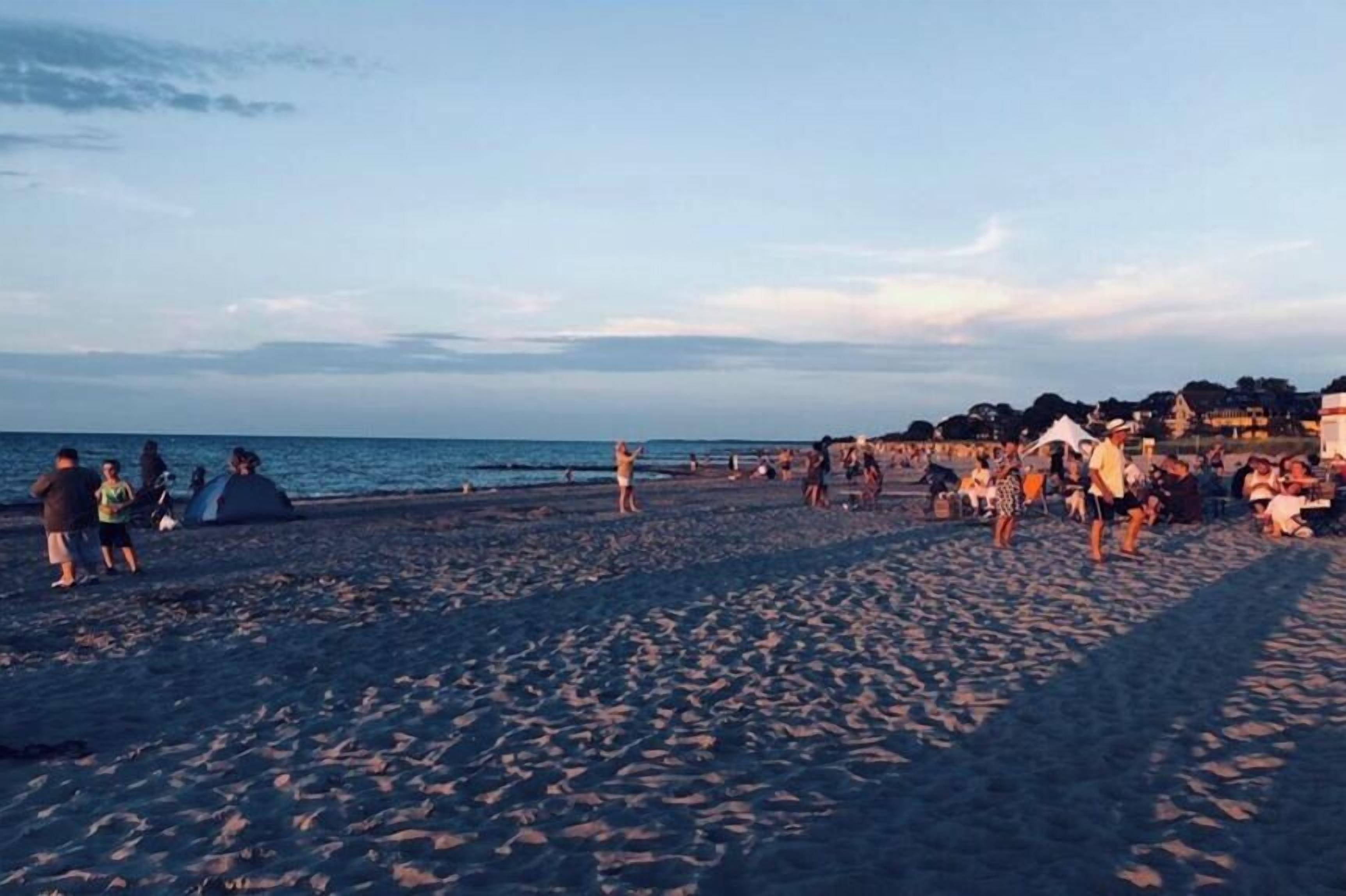 Une plage avec des gens, des tentes et un ciel dégagé.