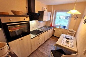 A compact kitchen with a built-in oven, a sink, and a dining area with a table and chairs. - "Holiday apartment at Kirr" (Zingst)
