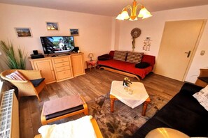Ein Wohnzimmer mit Fernseher, einer Couch und einem kleinen Tisch mit Dekoration.