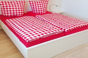 Ein Bett mit roter Matratze und karierter Bettwäsche.