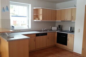 A kitchen with wooden cabinets, a dishwasher, a sink, and a window. - ||-----------------------Bodden Swallow------------------|| (Born am Darss)