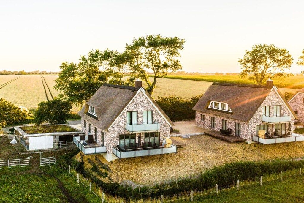 Een moderne boerderijwoning met een stenen gevel, grote ramen en een plat dak.