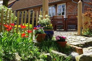 Un jardin avec une clôture en bois, un banc et des plantes en pot.