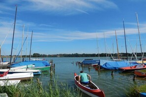 A calm lake with several boats docked, a person in a canoe, and a clear sky. - 3 holiday farm at Hemmelsdorfersee (Offendorf)