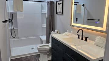 A modern bathroom with a shower, toilet, and vanity.
