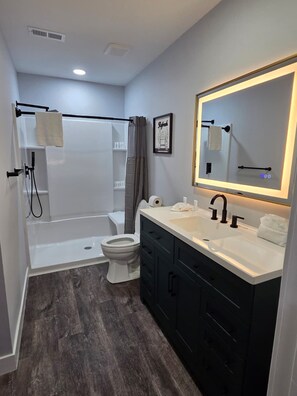 A modern bathroom with a shower, toilet, and vanity. - Pineville Spacious 2BR Home (Pineville)