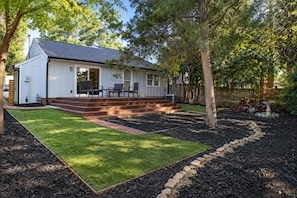 A house with a covered patio, a lawn, and a garden area with mulch and stepping stones.