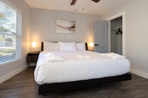 A hotel room with a large bed, bedside lamps, a painting on the wall, and a closet.