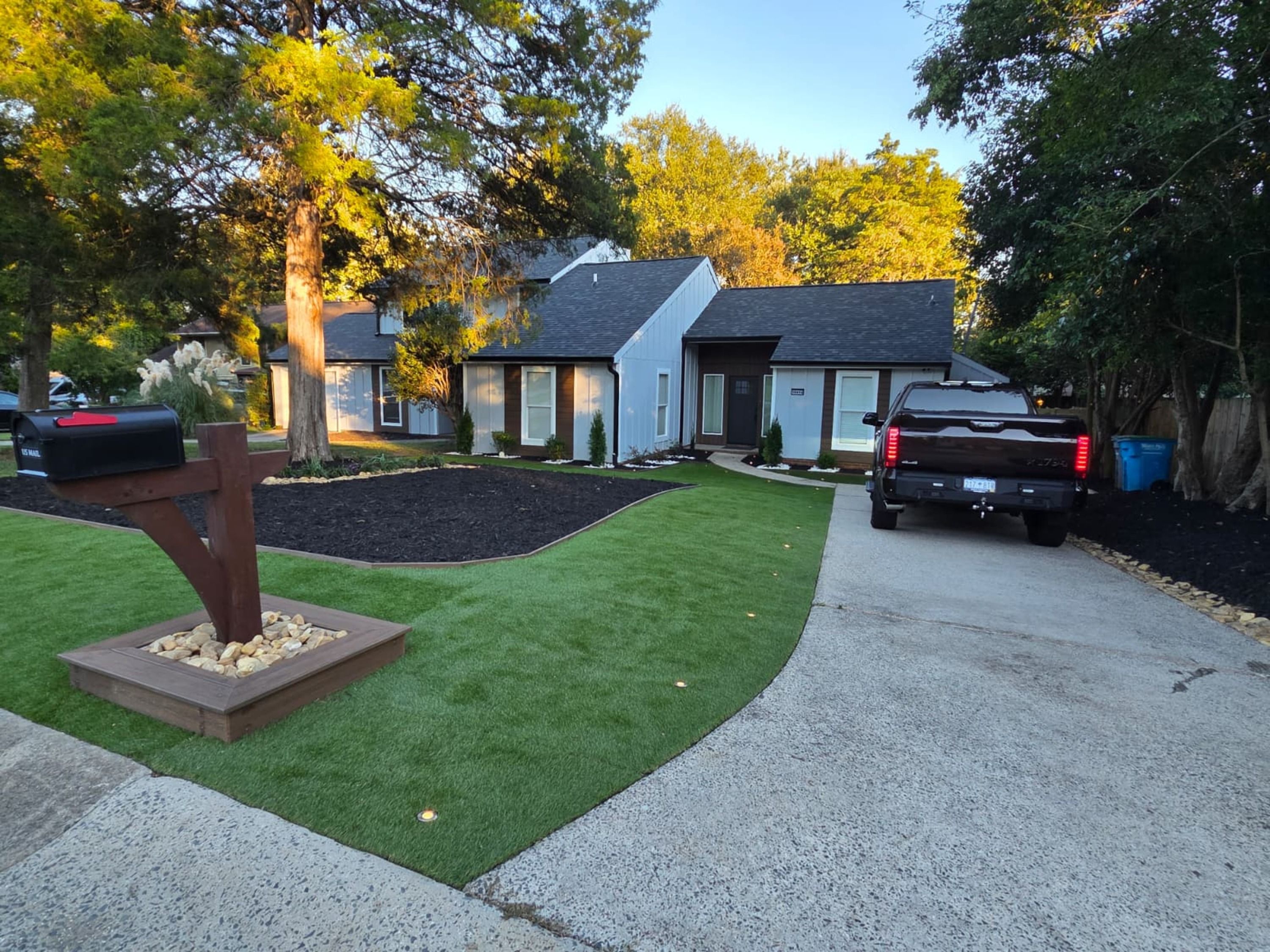 A residential driveway with a mailbox, a truck, and a well-maintained lawn.