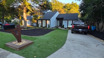 A residential driveway with a mailbox, a truck, and a well-maintained lawn.