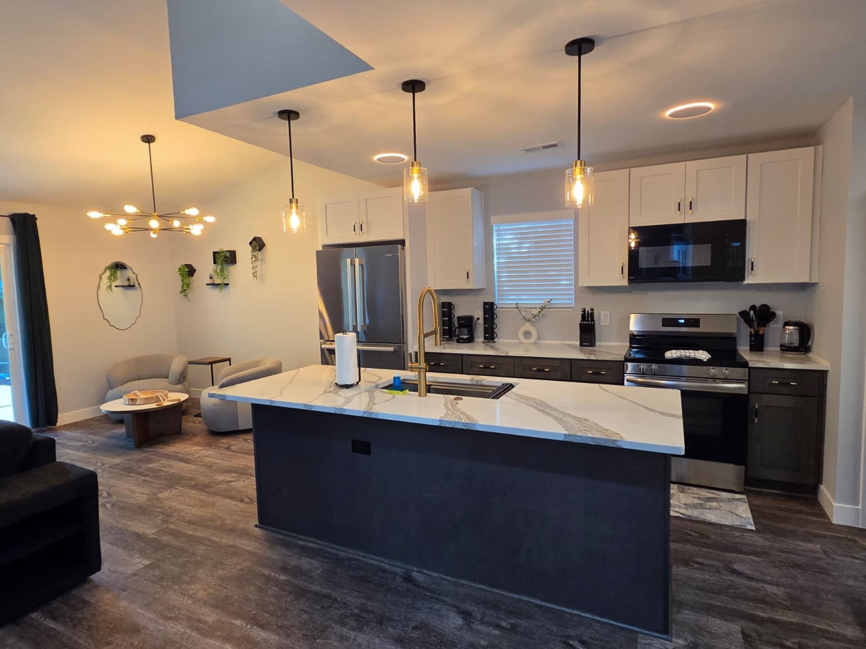 A modern kitchen with a central island, stainless steel appliances, pendant lighting, and a minimalist design.