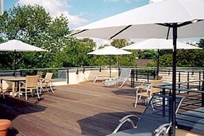 An outdoor deck with tables and chairs, umbrellas, and a wooden floor. - Holiday apartment with 1 bedroom (Dierhagen)