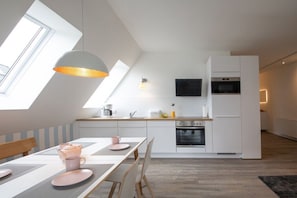 A modern kitchen with a dining area, skylight, built-in oven, and a flat-screen TV. - Hyggehuus - Timmendorfer Strand (Timmendorfer Strand)