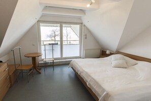 Ein Schlafzimmer mit einem Bett, einem kleinen Tisch, einem Stuhl und einem Fenster.
