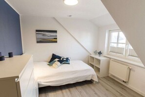 A bedroom with a bed, a bedside table, a window, and a radiator. - Holiday home with 3 bedrooms (Born a. Darß)