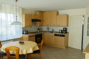 Una cocina con muebles de madera, estufa, lavavajillas y una mesa de comedor con sillas.