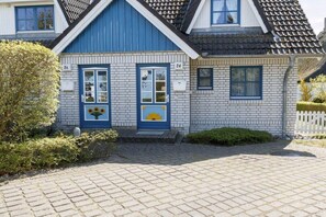 A two-story house with a blue door and a number '20' on the wall. - Holiday home with 2 bedrooms (Born a. Darß)