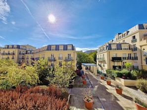 A residential building with multiple balconies, a paved pathway, and potted plants. - Little Nashville - 3 min from Disney - 35 min from Paris (Chessy)