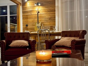 A room with two leather armchairs, a table with a candle, a guitar, and a book titled 'WALLSNYE'. - Little Nashville - 3 min from Disney - 35 min from Paris (Chessy)