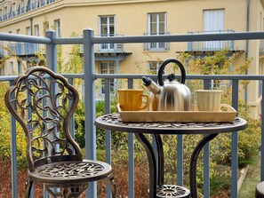 A balcony with a metal chair, a small table with a tray holding a kettle, cups, and a teapot. - Little Nashville - 3 min from Disney - 35 min from Paris (Chessy)