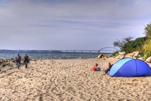 A beach with a tent and a bridge in the background. - Holiday home with 1 bedroom (Fehmarn OT Wulfen)