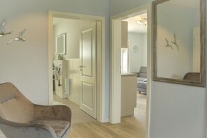 Een kamer met een stoel, een deur naar een badkamer en een spiegel aan de muur.