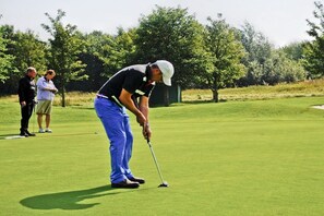 A person on a golf course with a putting green, trees, and a clear sky. - Holiday home with 1 bedroom (Fehmarn OT Wulfen)