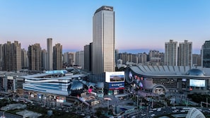 Um edifício alto com fachada de vidro moderna, rodeado por um skyline urbano denso com diversos edifícios comerciais.