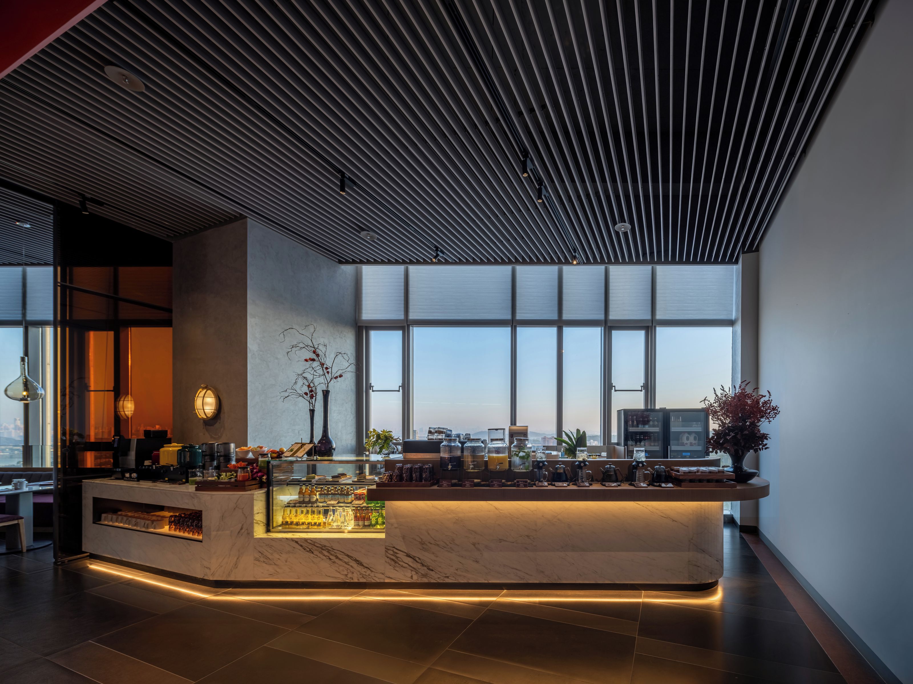 Un espacio moderno de bar con encimera de mármol, ventanas amplias y vista a la ciudad.