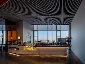 A modern bar area with a marble countertop, large windows, and a city view.