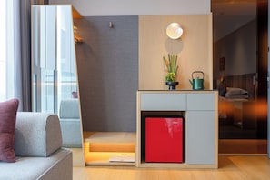A modern living room with a sofa, a red cabinet, a small table, and a wall-mounted light fixture.