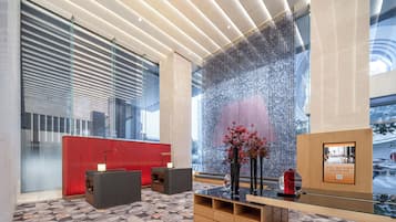 A modern reception area with a patterned carpet, a red reception desk, and a large glass wall with a decorative screen.