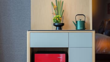 A compact, modern room with a wooden desk, a red cabinet, a potted plant, and a kettle.