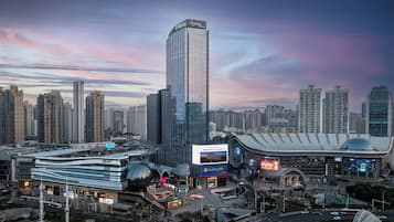 A cityscape with modern high-rise buildings, a distinctive curved building with a dome, and a large billboard.