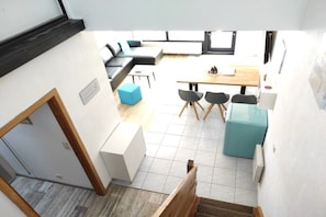 Un espace de vie compact comprenant un coin repas, un canapé, une petite table et un escalier.