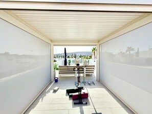 A balcony with a view of the city, a bench, and exercise equipment. - Villa Soleada La Finca Golf by Villas&You (Algorfa)