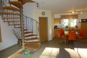A modern kitchen with a dining area, a spiral staircase, and a clock on the wall. - Beach butterfly Zingst (Zingst  (Fischland Darß))