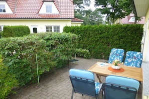 A patio with a table and chairs, surrounded by greenery and a hedge. - Beach butterfly Zingst (Zingst  (Fischland Darß))