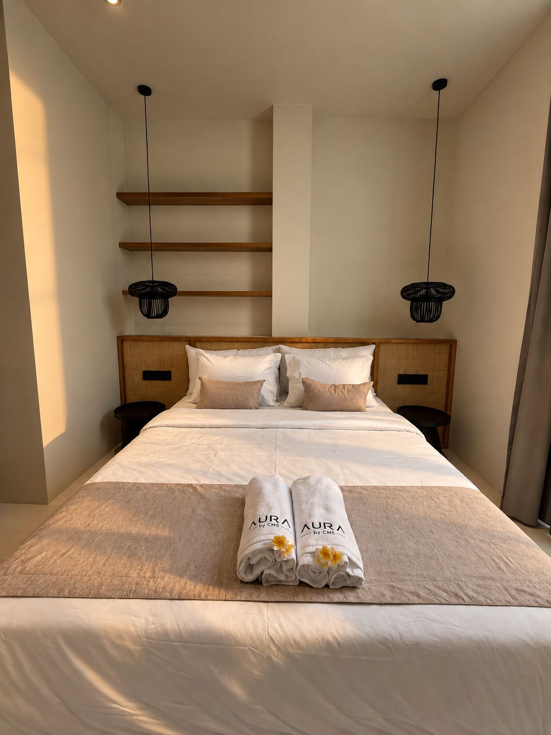 A neatly made bed with a headboard, two bedside tables, and two hanging lamps.